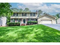 Charming two-story home with manicured lawn, attached garage, and classic architectural details at 1206 Tred Avon Sw Way, Lilburn, GA 30047