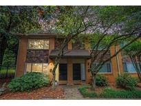 Charming brick townhome featuring stone accents and a well-manicured front yard with mature trees and lush greenery at 100 Biscayne Nw Dr # A1, Atlanta, GA 30309