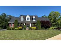 Charming red brick home featuring manicured lawn and mature landscaping at 5945 Bannister Rd, Cumming, GA 30028