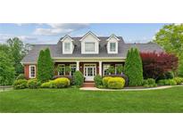 Charming brick home featuring dormer windows, manicured landscaping, and a welcoming covered front porch at 5945 Bannister Rd, Cumming, GA 30028