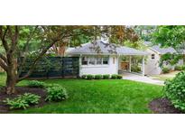 Charming white brick home featuring a lush green lawn, covered driveway, and black horizontal slat fence at 2298 Pembrook Pl, Atlanta, GA 30324