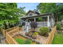 Charming bungalow-style home with a welcoming front porch, landscaped yard, and quaint wooden fence at 1063 Manigault Se St, Atlanta, GA 30316
