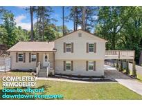 Remodeled two-story home boasting a welcoming front yard, charming shutters and an inviting covered parking area at 3050 Woodland Nw Dr, Kennesaw, GA 30152