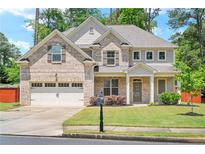 Two-story brick home featuring an attached garage, a well-manicured lawn, and mature trees at 4093 Groveland Park Dr, Powder Springs, GA 30127