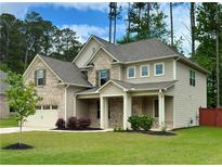 Two-story home with a combination of brick and siding, a well-manicured lawn, and a covered front porch at 4093 Groveland Park Dr, Powder Springs, GA 30127