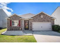 Charming single-story home with brick facade, attached garage, manicured lawn and vibrant red window shutters at 1907 Sea Oats Dr, Hampton, GA 30228