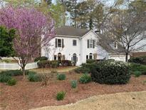 Charming two-story home with white picket fence and mature landscaping, including a beautiful flowering tree at 5440 Cameron Forest Pkwy, Johns Creek, GA 30022