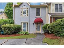 Charming townhome with a red awning over the front door and manicured landscaping at 2682 Arbor Glen Pl., Marietta, GA 30066