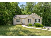 Charming single-story home with well-maintained lawn and mature landscaping, and concrete walkway at 175 Hearth Way, Fairburn, GA 30213