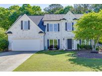 Charming two-story white brick home with black shutters, manicured lawn, and mature trees at 1755 Waters Ferry Dr, Lawrenceville, GA 30043