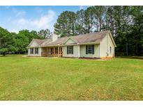 Charming single-story home with a welcoming front porch and a spacious green lawn surrounded by mature trees at 102 Aristocratic Way, Locust Grove, GA 30248