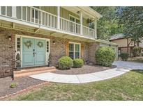 Charming brick home with a welcoming front entrance, light blue double doors, and a second-story balcony at 1080 Northshore Dr, Roswell, GA 30076