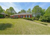 Beautiful red brick home featuring a well-maintained lawn and mature trees at 1420 Arblay Pl, Loganville, GA 30052
