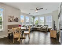 Bright living room boasts many windows, dark floors, ceiling fan, and neutral colored L-shaped couch at 1300 Dekalb Ne Ave # 731, Atlanta, GA 30307