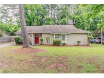 Charming single story home with brick accents, manicured landscaping and a bright red front door at 2469 Newgate Dr, Decatur, GA 30035