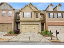 Charming townhome featuring a two-car garage, stone accents and manicured landscaping at 2647 Sardis Chase Ct, Buford, GA 30519