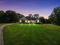 Charming brick home boasts lush lawn, mature trees, and picturesque views at dusk at 70 Lake Charles Xing, Covington, GA 30016