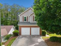 Two-story home featuring a two-car garage, neutral siding, brick accents, and mature landscaping at 164 Stoneforest Dr, Woodstock, GA 30189