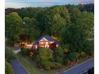 A beautiful brick two-story home surrounded by lush landscaping and mature trees at 3102 Royal Troon, Woodstock, GA 30189