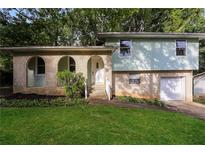 Split-level home with brick accents, arched entryway, and lush green lawn at 8857 Ashwood Dr, Riverdale, GA 30274