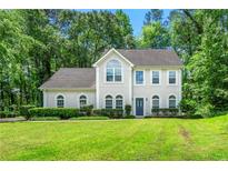 Charming two-story home with a well-manicured lawn and lush green trees in a quiet suburban neighborhood at 2312 Mahogany Glen Pl, Lawrenceville, GA 30043