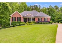 Charming red brick home featuring mature landscaping and a sprawling green lawn at 7511 Biltmore Ln, Douglasville, GA 30135