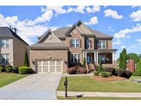 Beautiful brick home with a two-car garage, landscaped yard, and charming front porch at 11240 Avery Cove Ct, Alpharetta, GA 30022