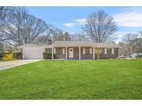 Charming brick ranch-style home with a well-manicured lawn and an attached garage at 897 Marie Sw Ln, Conyers, GA 30094