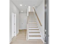 Bright entryway featuring white-painted walls, hardwood floors, and a staircase with natural wood handrail at 2592 Alcovy Ne Trl, Marietta, GA 30066