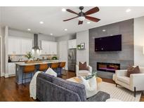 Open-concept living room featuring a fireplace, a ceiling fan, and a modern kitchen island with barstool seating at 1202 Hardee Ne St, Atlanta, GA 30307