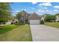 Charming brick home with a well-manicured lawn, two car garage, and a beautifully landscaped front yard at 4050 Pleasant Woods Dr, Cumming, GA 30028