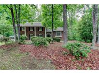 Charming brick two-story home with black shutters surrounded by lush greenery and mature trees at 3539 Evans Mill Rd, Lithonia, GA 30038