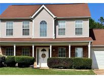 Charming two-story home featuring a brick facade and covered front porch with a manicured lawn and mature shrubs at 5458 Stagecoach Rd, Ellenwood, GA 30294