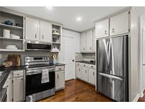 Well-lit kitchen with stainless steel appliances, hardwood floors, and plentiful cabinet storage at 1320 Country Acres Ln, Lawrenceville, GA 30045
