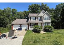 Two-story home featuring a two-car garage, front porch, and manicured front yard landscaping at 4649 Camelot Dr, Douglasville, GA 30135