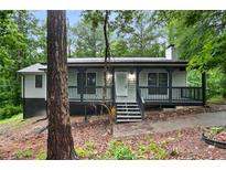Charming single-story home with a welcoming front porch and neutral siding, nestled among lush trees at 6032 Lakeshore Se Dr, Mableton, GA 30126