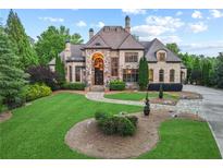 Beautiful stone home with manicured lawn and lush landscaping on a sunny day at 878 Middle Fork Trl, Suwanee, GA 30024