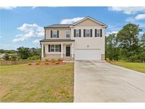 Charming two-story home featuring neutral siding, black shutters, a two-car garage, and a well manicured lawn at 294 Ralph Still Rd, Dacula, GA 30019