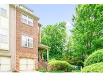 Charming brick townhome featuring a garage and front porch with lush landscaping at 1996 Cobblestone Ne Cir, Atlanta, GA 30319