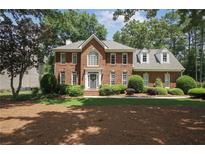 Charming two-story brick home with a well-manicured lawn and mature trees at 1915 Milfield Cir, Snellville, GA 30078