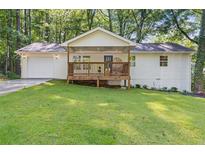 Charming ranch-style home with a covered front porch and attached garage, surrounded by lush greenery and mature trees at 2856 Bay Leaf Se Dr, Conyers, GA 30094