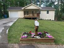 Charming one-story home with a covered front porch, attached garage, green lawn, and a decorative mailbox planter at 2856 Bay Leaf Se Dr, Conyers, GA 30094
