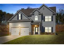 Charming two-story home with gray siding, black shutters, two-car garage, and well-manicured lawn at 33 N Village Cir, Rydal, GA 30171
