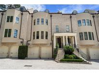 Elegant brick townhome featuring multiple garage spaces, arched windows, and a welcoming front porch with stately columns at 122 Old Ivy Ne Rd # 17, Atlanta, GA 30342