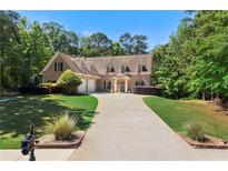 Charming brick home featuring a long driveway, well-manicured lawn, and mature trees at 7401 Cherry Blossom Way, Winston, GA 30187
