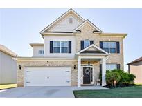 Charming two-story home features a brick facade, two-car garage, and meticulously maintained front yard at 165 Craines Vw, Covington, GA 30014