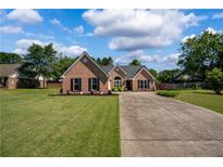 Charming brick home featuring a manicured lawn and long driveway on a sunny day at 7095 Valley Landing Ct, Cumming, GA 30041