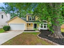 Charming yellow two-story home with a well-maintained yard and attached garage and a black front door at 194 Beaverwood Ct, Lawrenceville, GA 30044