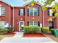 Charming brick townhome with black shutters, well-manicured bushes, and mulch at 2430 Piering Dr, Lithonia, GA 30038