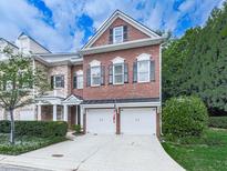 Charming brick townhome featuring a two-car garage and well-manicured landscaping at 5605 Waters Edge Trl, Roswell, GA 30075